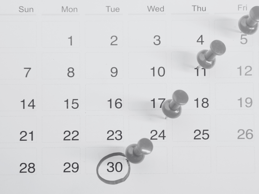 Calendario mensual con fechas marcadas por chinchetas, ilustrando una estrategia de publicación bien distribuida