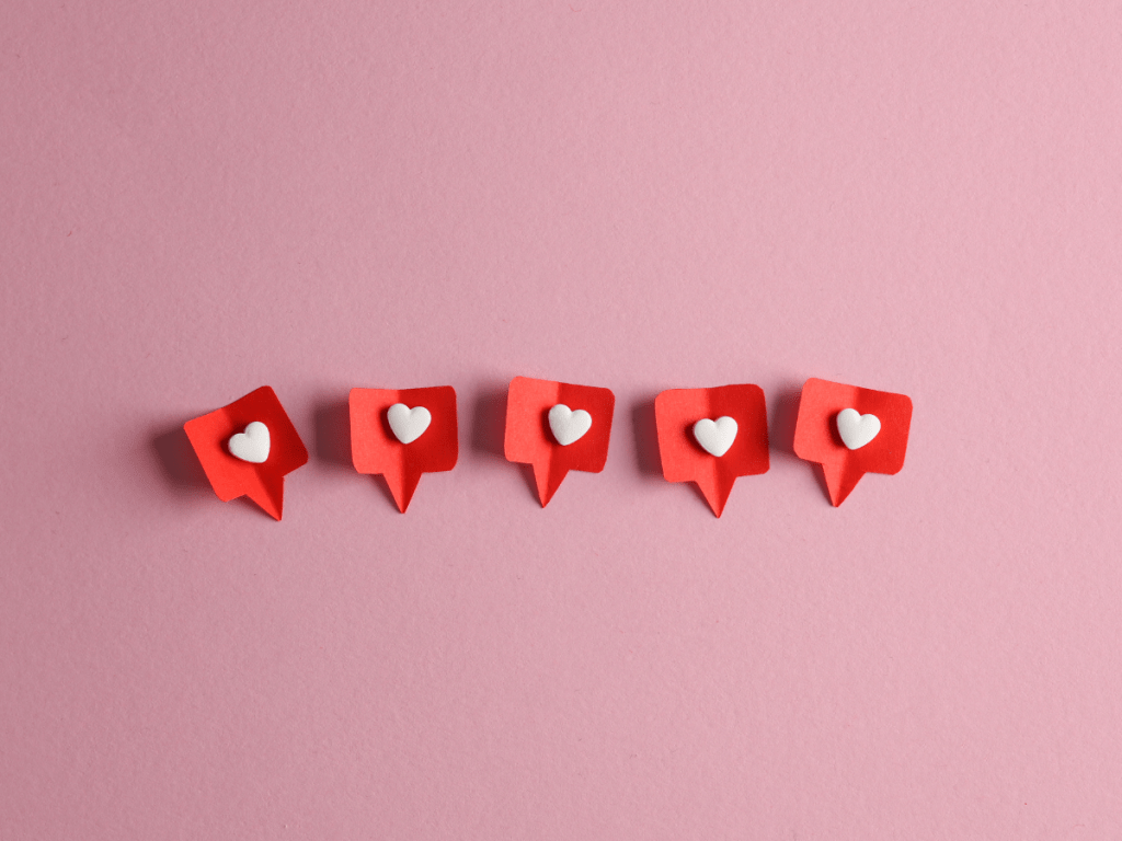 Iconos de “me gusta” alineados sobre fondo rosa que representan la interacción en redes sociales.